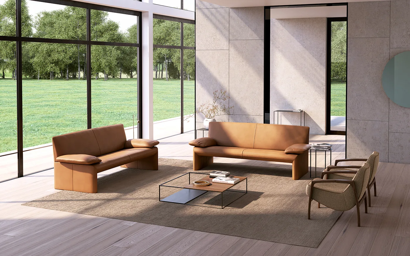 JORI Linea Sofas in cognacfarbenem Leder mit offenem Untergestell vor großen Fenstern