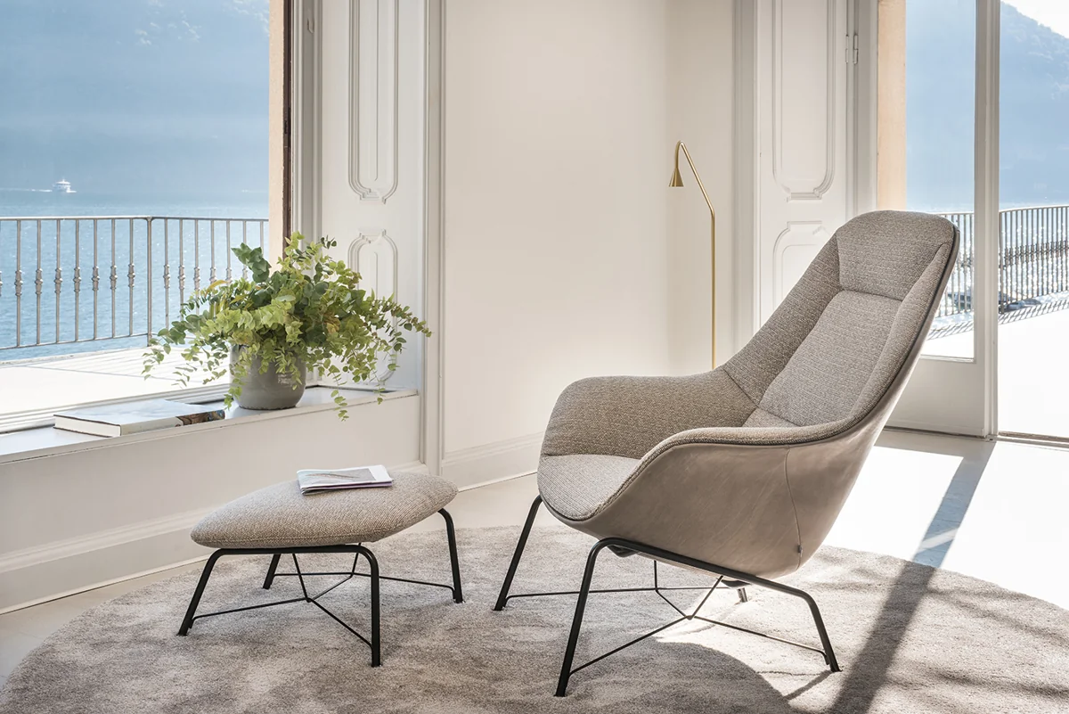 Heller Prelude Lounge mit filigranen Rohrfüßen und passendem Hocker vor einem Fenster