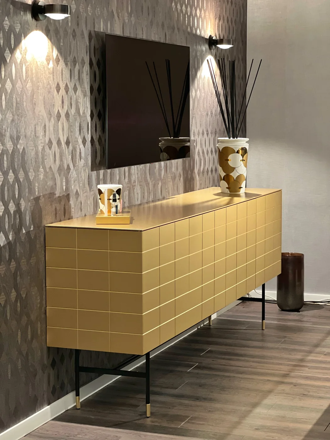 Goldfarbenes Kettnaker SOMA-Sideboard auf dunklem Fußgestell unter einem Fernseher